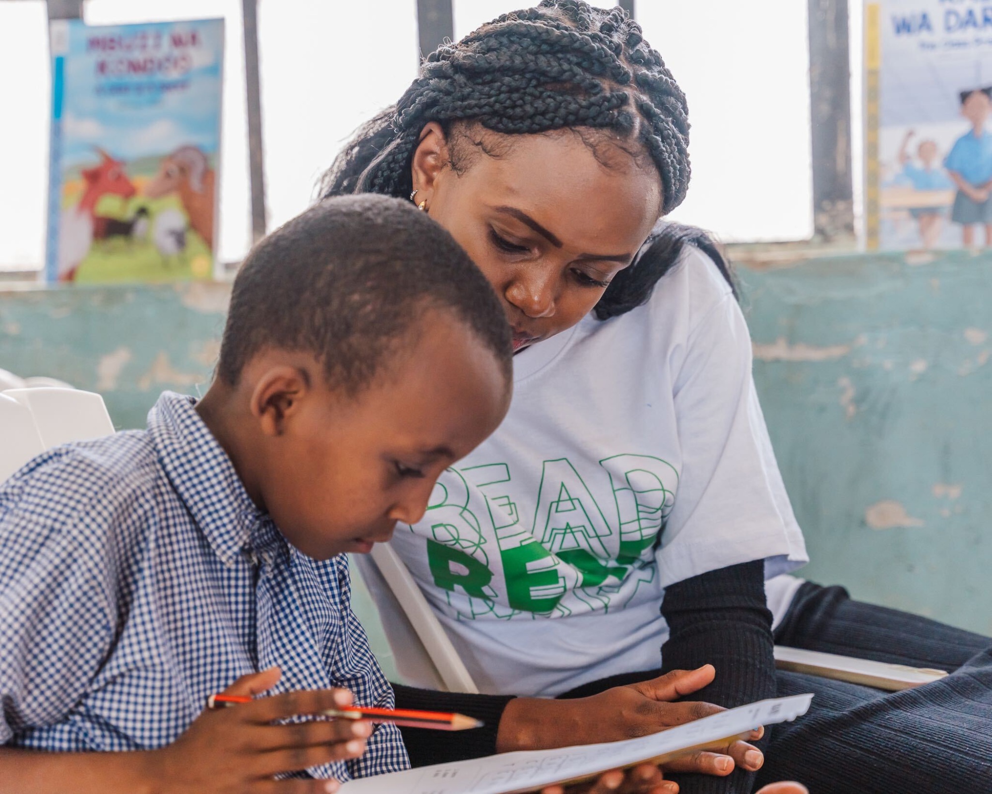 A grade 2 student being guided on words in the puzzle by Carolyne Maina - NABU Literacy Champion